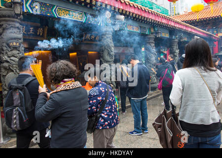 faithful in prayer while offering incense sticks  in  Sik Sik Yuen Wong Tai Sin temple in Hong Kong Stock Photo