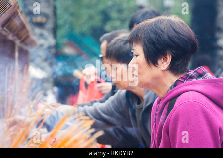 faithful in prayer while offering incense sticks  in  Sik Sik Yuen Wong Tai Sin temple in Hong Kong Stock Photo