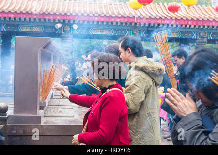 faithful in prayer while offering incense sticks  in  Sik Sik Yuen Wong Tai Sin temple in Hong Kong Stock Photo