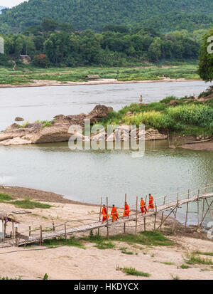 LUANG PRABANG, LAOS - MAY 16 2015: Buddhist monks cross a wooden bridge on the Nam Ou river in Luang Prabang in north Laos Stock Photo