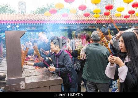 faithful in prayer while offering incense sticks  in  Sik Sik Yuen Wong Tai Sin temple in Hong Kong Stock Photo