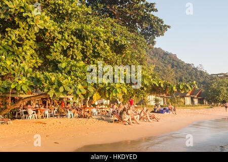 KOH CHANG, THAILAND - DECEMBER 29, 2015: Tourists enjoy a drink in a beach bar during sunset over white sand beach in Koh Chang. The island is situate Stock Photo