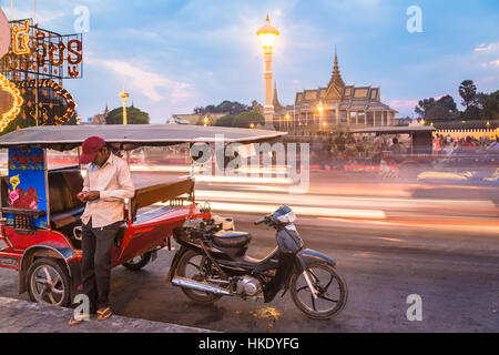 PHNOM PENH, CAMBODIA - JANUARY 24, 2016: A tuk tuk driver waits for customer in front of the Royal Palace in Phnom Penh, Cambodia capital city. Stock Photo