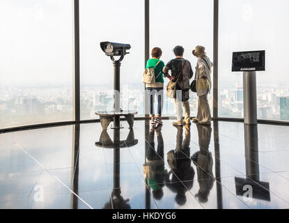HO CHI MINH CITY, VIETNAM - FEBRUARY 2, 2016: 3 Asian female tourists enjoy the view over Ho Chi Minh City from the observatory in a city skyscraper. Stock Photo