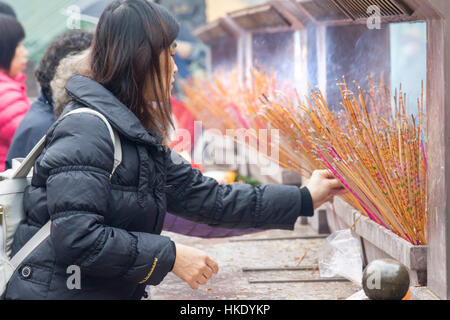 faithful in prayer while offering incense sticks in  Sik Sik Yuen Wong Tai Sin temple in Hong Kong Stock Photo