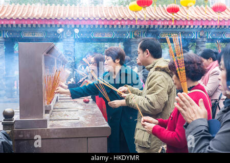 faithful in prayer while offering incense sticks  in Sik Sik Yuen Wong Tai Sin temple in Hong Kong Stock Photo