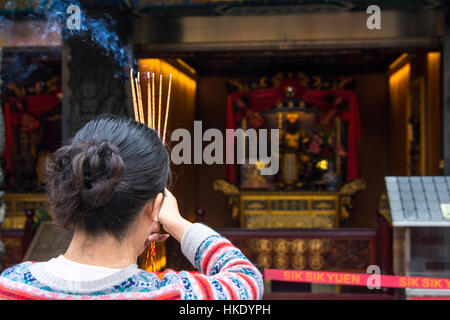 faithful in prayer while offering incense sticks  in Sik Sik Yuen Wong Tai Sin temple in Hong Kong Stock Photo