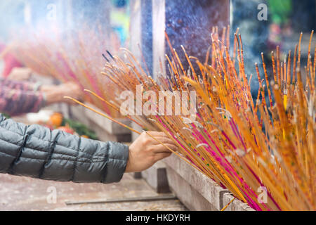 faithful in prayer while offering incense sticks  in Sik Sik Yuen Wong Tai Sin temple in Hong Kong Stock Photo