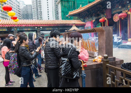 faithful in prayer while offering incense sticks  in   Sik Sik Yuen Wong Tai Sin temple in Hong Kong Stock Photo