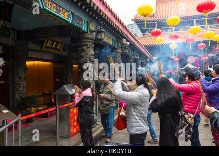 faithful in prayer while offering incense sticks  in  Sik Sik Yuen Wong Tai Sin temple in Hong Kong Stock Photo