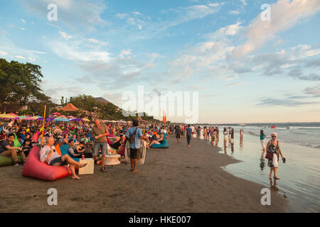 KUTA, INDONESIA - FEBRUARY 19, 2016: A large crowd of tourists, Indonesian and foreigners, enjoy the sunset at a beach bar on Kuta beach in Seminyak, 