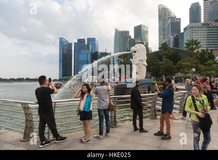 SINGAPORE, SINGAPORE - FEBRUARY 22 2016: Tourists take photos in front of the city famous skyline and the Merlion statue.