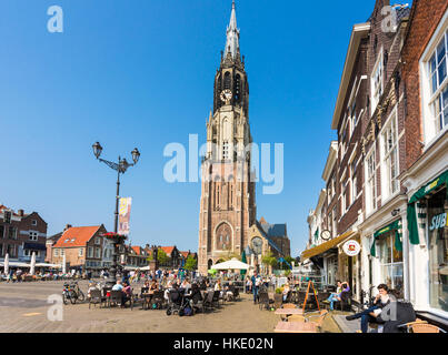 DELFT, THE NETHERLANDS - MAY 28, 2016: People enjoy a coffee on Delft old town main square in front of the tall new church (Nieuwe Kerk). Stock Photo