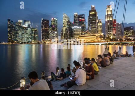 SINGAPORE, SINGAPORE - FEBRUARY 22 2016: Tourists enjoy the view on the famous Singapore skyline from the marina. Shot with long exposure to freeze th