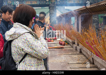 faithful in prayer while offering incense sticks  Sik Sik Yuen Wong Tai Sin temple in Hong Kong Stock Photo