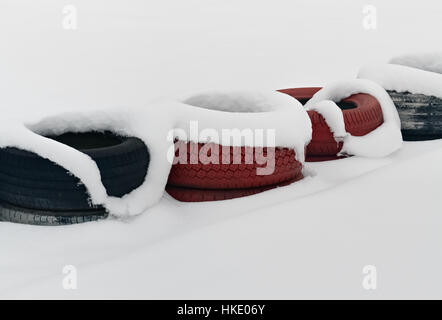 Several car tires under snow as a safeguard on the racetrack Stock Photo