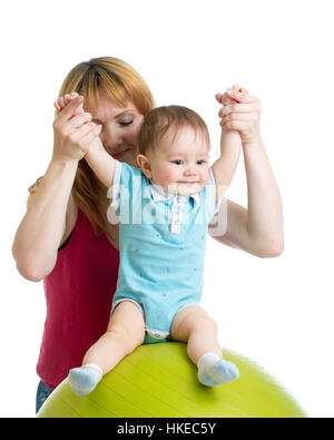 Mother with happy baby doing exercises with gymnastic ball. Concept of caring for kids health. Stock Photo