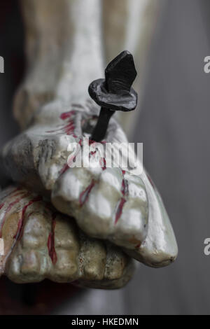 Closeup of feet of Jesus Christ nailed to the cross during the crucifixion. Shallow depth of field. Defocused blurry background. Stock Photo