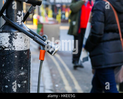Broad Street, Oxford, United Kingdom, January 22, 2017: U-lock secure bicycle locks on light post on Broad street, Oxford city centre, England Stock Photo