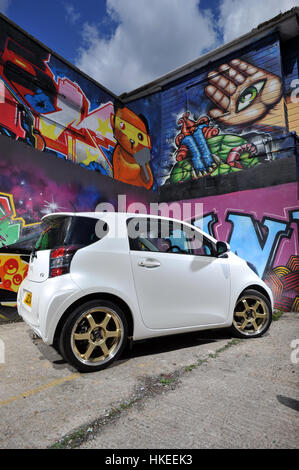 Modified Toyota IQ sub compact city car and graffiti wall Stock Photo
