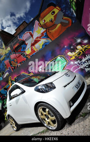 Modified Toyota IQ sub compact city car and graffiti wall Stock Photo