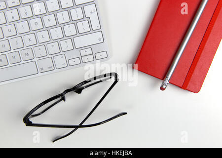 Glasses, computer keyboard and notebook on white office desktop Stock Photo