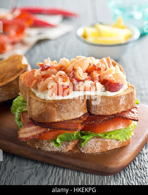 A delicious lobster club sandwich with bacon, lettuce, tomato, and mayonnaise on toasted bread. Stock Photo