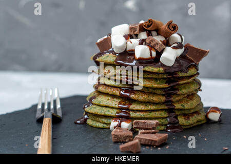 Non-traditional green sweet pancakes with chocolate and marshmallows. Love for a healthy desserts concept. Stock Photo