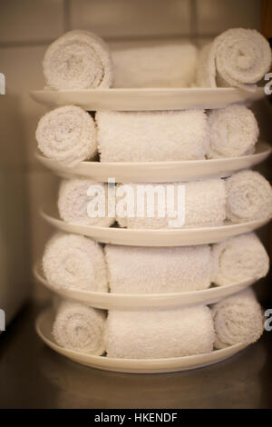 Rolled fluffy towels on shelf in bathroom Stock Photo by FabrikaPhoto