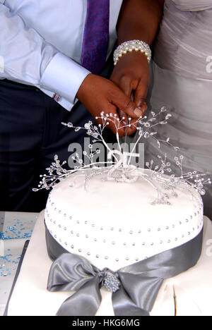 Caribbean couple cutting wedding cake together Stock Photo
