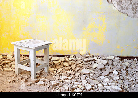 Old vintage wooden chair in an abandoned grunge room with cracked yellow cement mortar wall background. Grunge vintage interior. Stock Photo