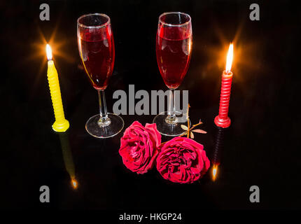 Romantic setup with burning candles red roses and red wine glasses in dark background. Stock Photo