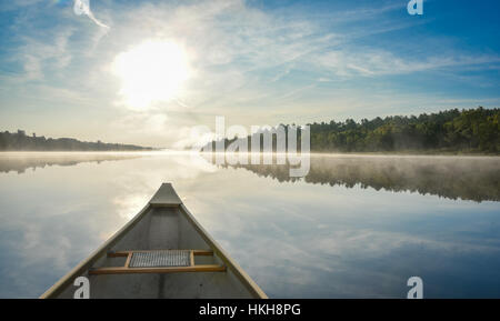 Canoe trip in the morning.  Brilliant and bright mid-summer sunshine morning, paddling a canoe in the middle of quiet, calm and peaceful Corry lake. Stock Photo