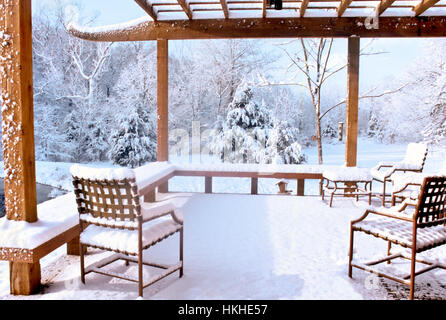 Peaceful snow-covered outdoor deck with snow on furniture looking out to the winter backyard outside home, Missouri, USA Stock Photo