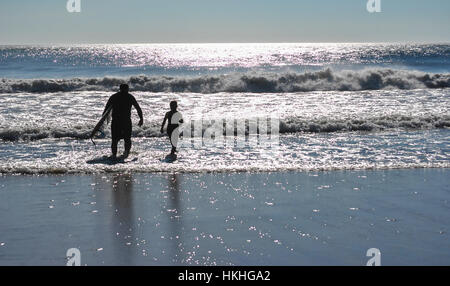 A father and son going out for an early morning surf lesson. Stock Photo