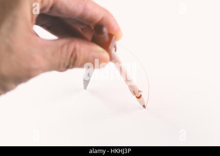 Close focus on pencil tip of compass instrument while drawing circle on white paper surface with orange warm light. Stock Photo