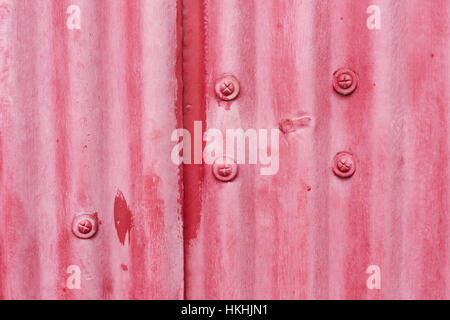 Close up of red painted metal with a corrugated texture and rivets Stock Photo