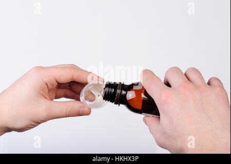 pouring cough syrup from bottle to cup on white Stock Photo