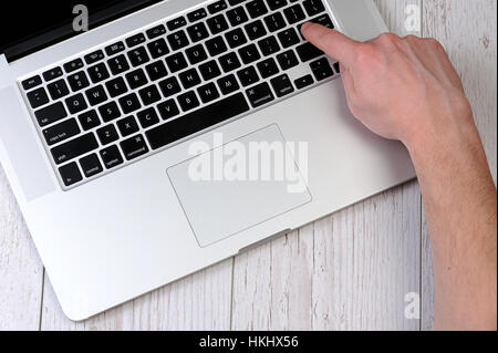 press enter button on laptop on wood table Stock Photo