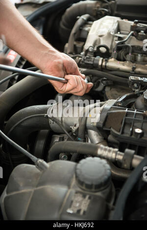Close up of incognito mechanic hands holding a tool while working on car engine Stock Photo