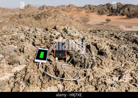 Smartphone charging with solar power bank with Dual USB port with Rocky mountain as background Stock Photo