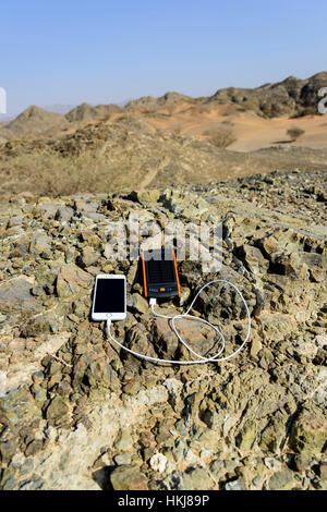 Smartphone charging with solar power bank with Dual USB port with Rocky mountain as background Stock Photo