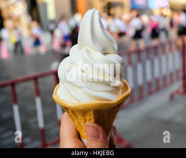 Ice cream cone held up in the big city Stock Photo