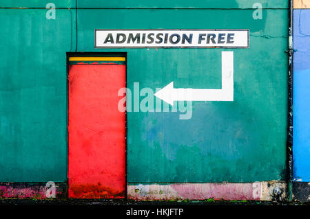 Red door on a green wall with a sign saying 'Admission Free' Stock Photo