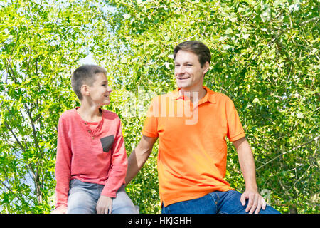 Father and son are talking smiling in summer park Stock Photo