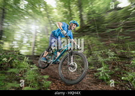 Mountain biker riding downhill in forest, Bavaria, Germany Stock Photo