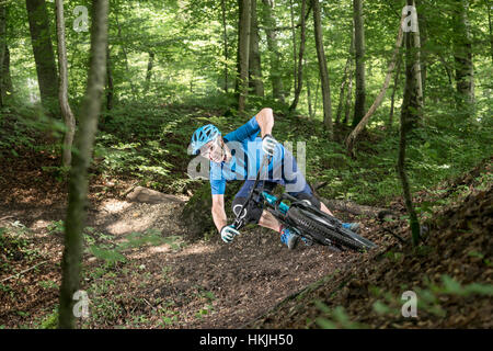 Mountain biker riding downhill in forest, Bavaria, Germany
