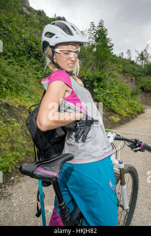 Mountainbiker with pain in back, Kampenwand, Bavaria, Germany Stock Photo