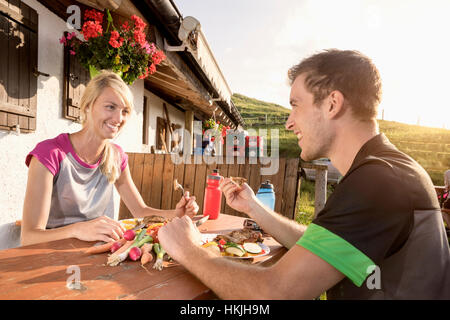 Young couple eating salad at alpine cabin, Kampenwand, Bavaria, Germany Stock Photo