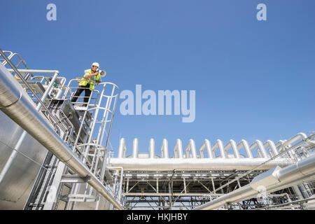 Low angle view of an engineer using a megaphone at geothermal power station, Bavaria, Germany Stock Photo